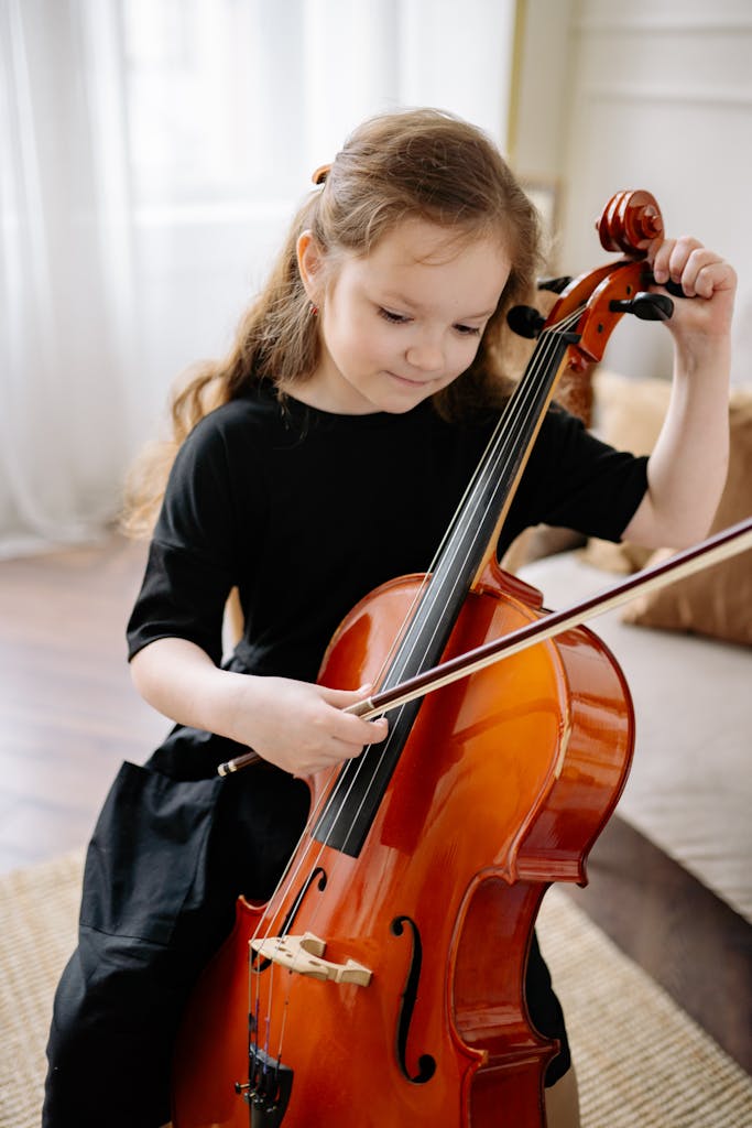 A young girl practicing cello indoors, showcasing musical talent and concentration.